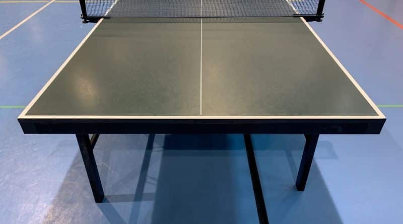 Eine Tischtennisplatte stet aufgebaut auf einem blauen Hallenboden