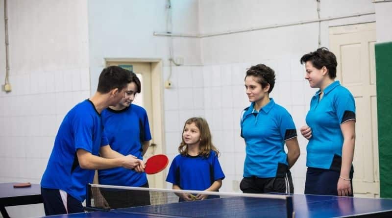 Tischtennis Trainer erklärt seiner Schülerin etwas