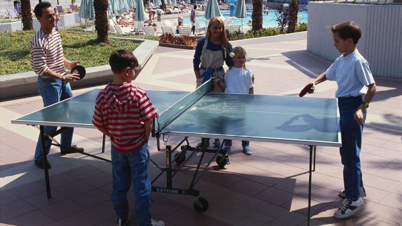 Eine Familie spielt draußen an einer Kettler Tischtennisplatte TIschtennis